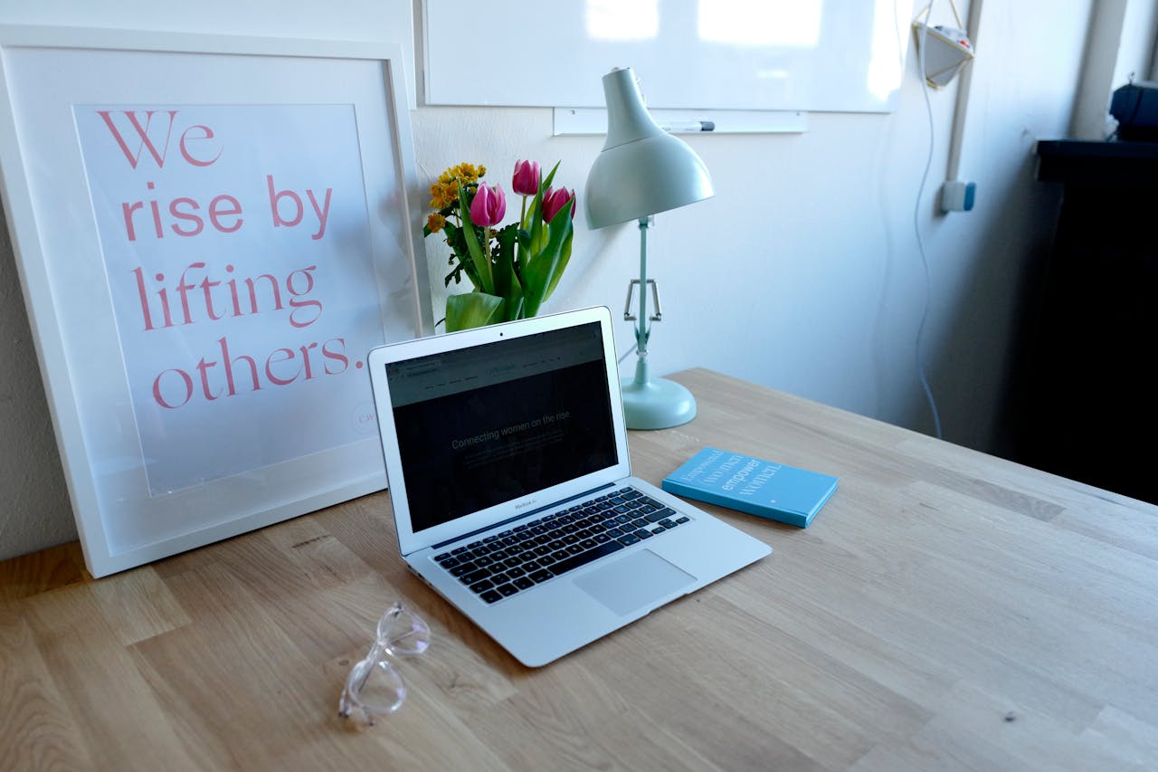 Stylish desk setup with a laptop, lamp, and framed quote for motivation.